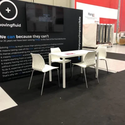 allestimento-con-tappeto-e-parete-nera-e-tavoli-e-sedie-uni-bianche