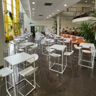 ampia-sala-con-pavimento-in-granito-infissi-gialli-piante-verdi-e-tavolini-e-sgabelli-alti-bianchi