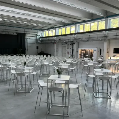 grande-sala-eventi-in-un-capannone-con-tavolini-alti-e-sgabelli-easy-bianchi