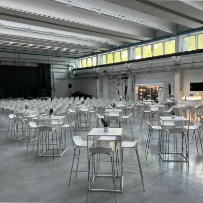 sala-conferenze-con-pavimento-grigio-palco-nero-sedute-bianche-e-tavoli-square-in-fondo-alla-sala