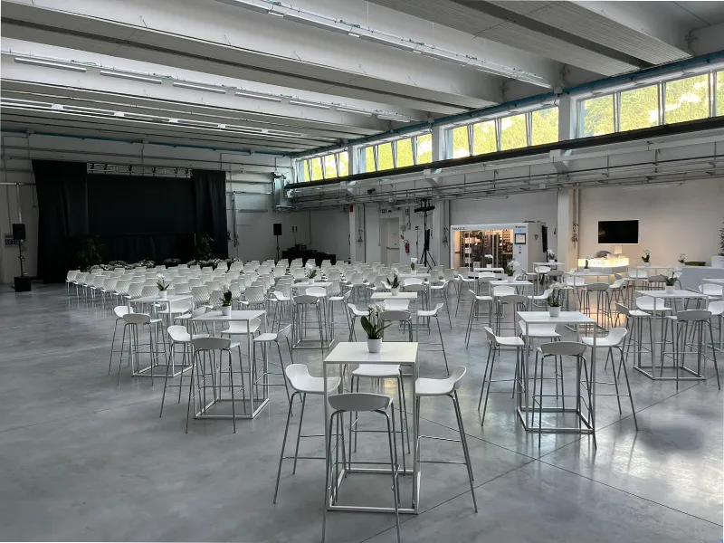 sala-conferenze-con-pavimento-grigio-palco-nero-sedute-bianche-e-tavoli-square-in-fondo-alla-sala