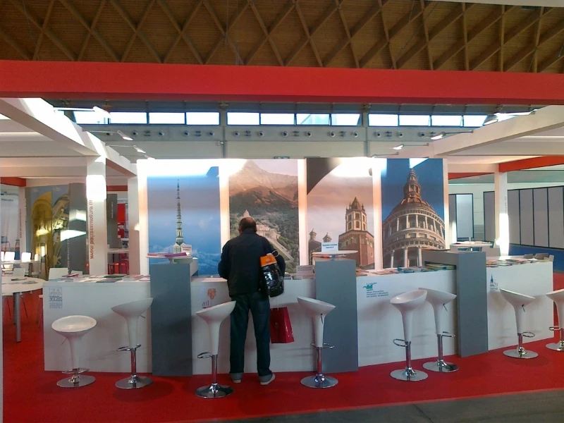 stand-con-bancone-bianco-illustrazioni-delle-citta-italiane-tappeto-rosso-e-sgabelli-bianchi-modello-bombo