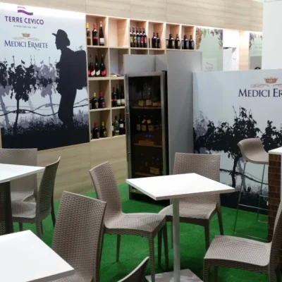 stand-con-erba-sintetica-vini-esposti-tavolini-bianchi-e-sedie-grige-bistrot